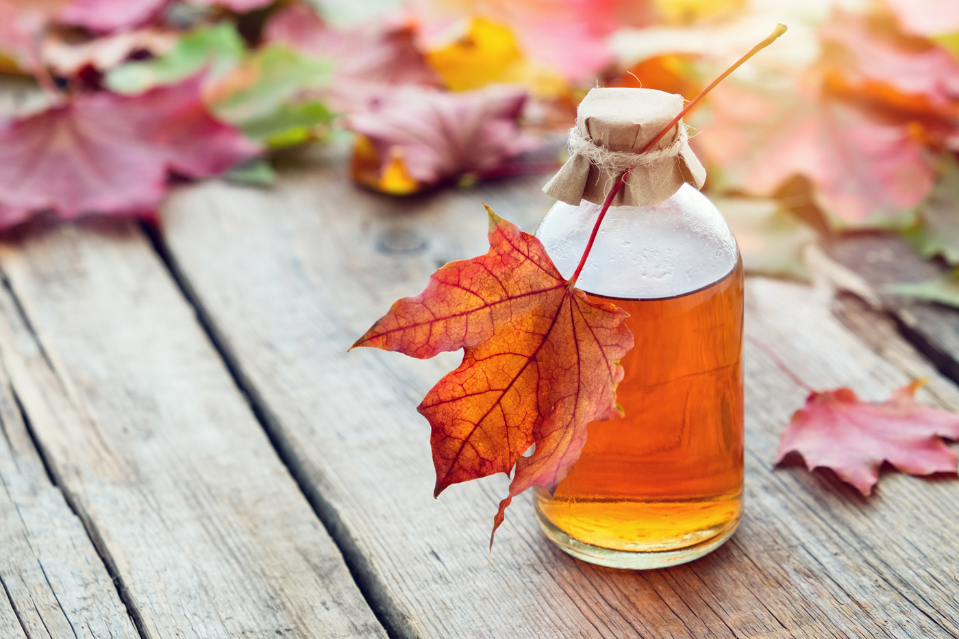 Maple syrup in bottle and fallen maple leaves. Maple syrup in bottle and fallen maple leaves.
