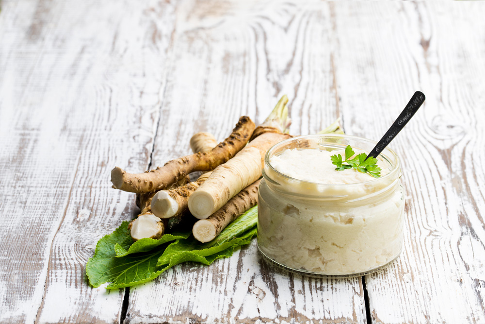 Spicy horseradish sauce in small glass jar on wooden table Spicy horseradish sauce in small glass jar on wooden table