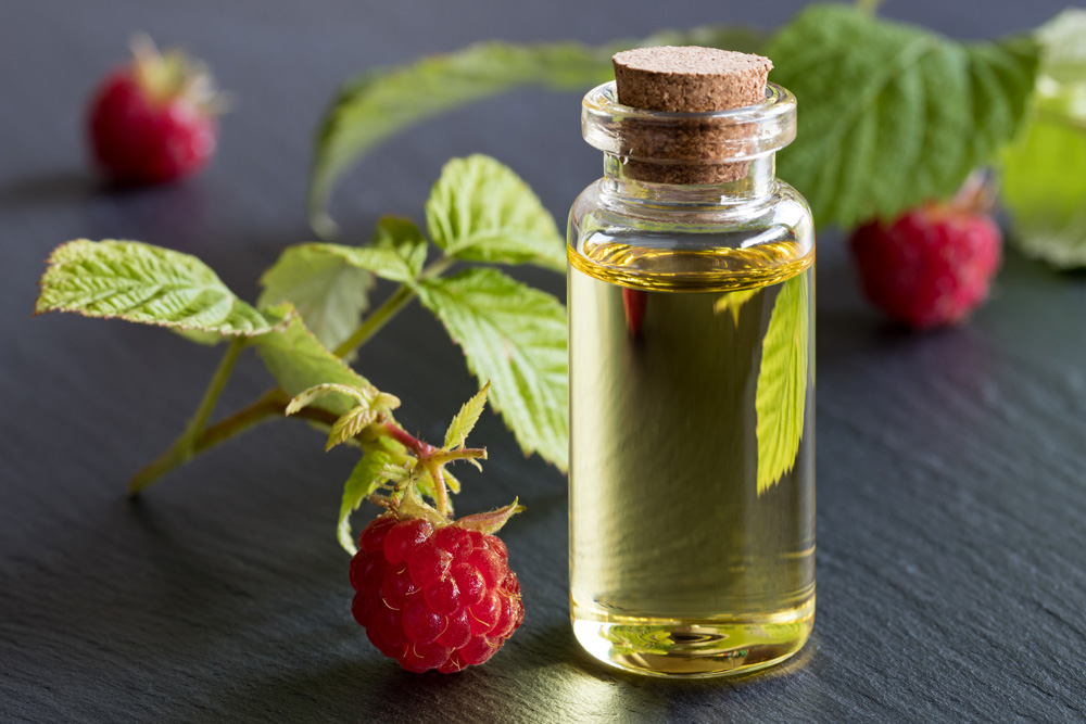 A bottle of raspberry seed oil with raspberries A bottle of raspberry seed oil with raspberries