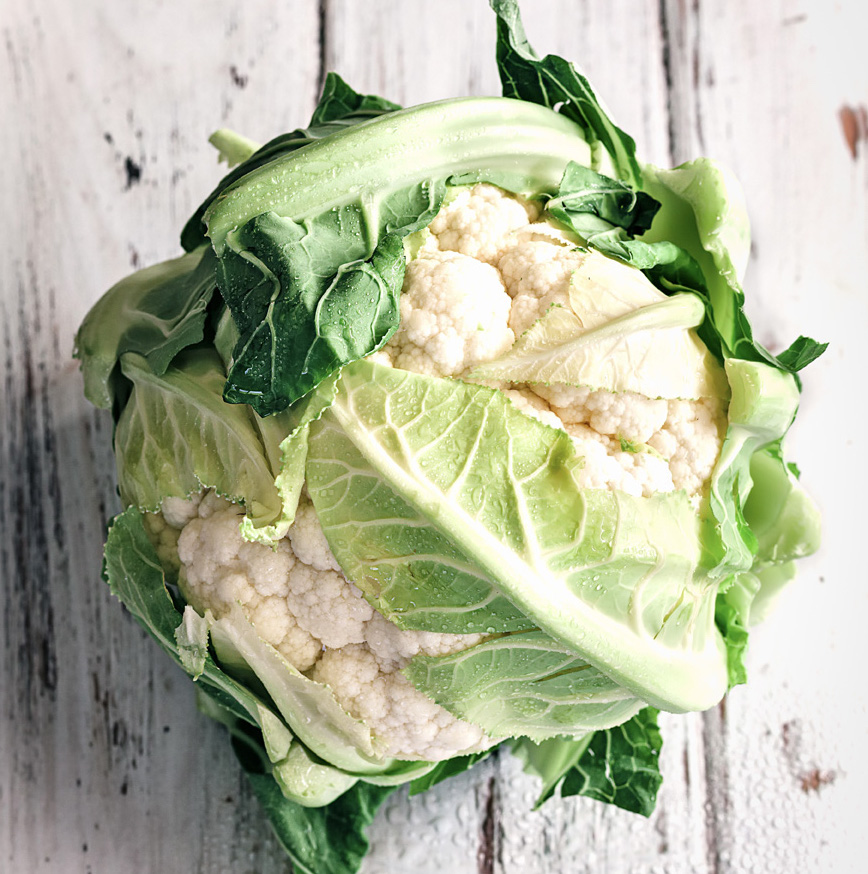 head of cauliflower on whitewashed table head of cauliflower on whitewashed table