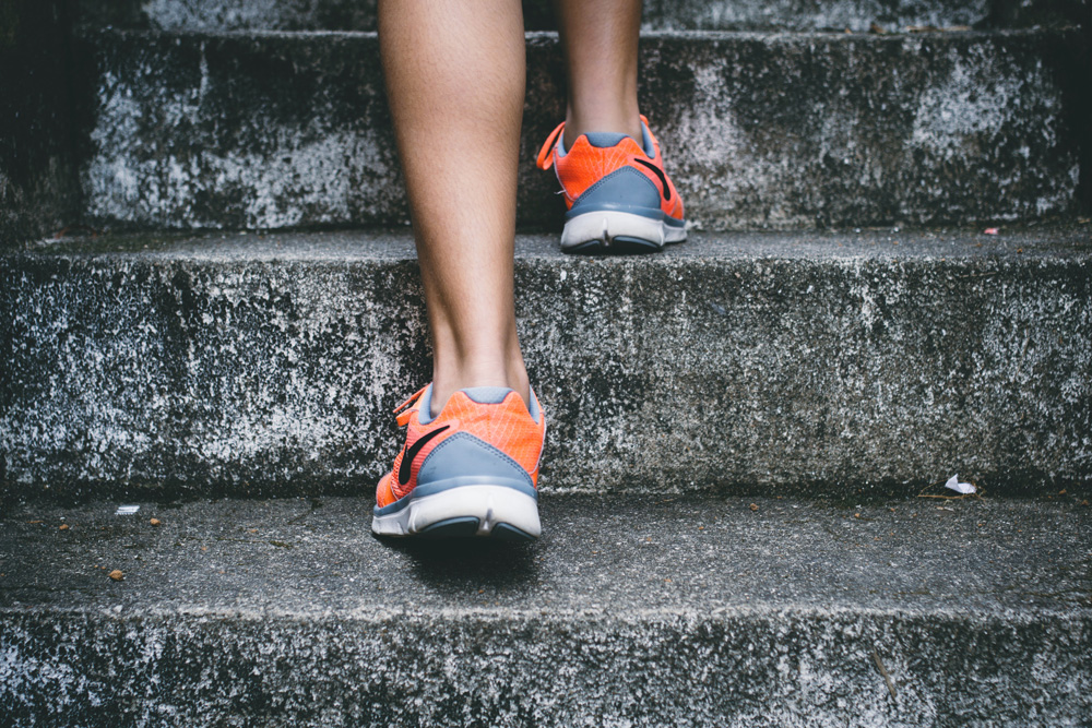 close up of womans feet in sneakers going upstairs close up of womans feet in sneakers going upstairs