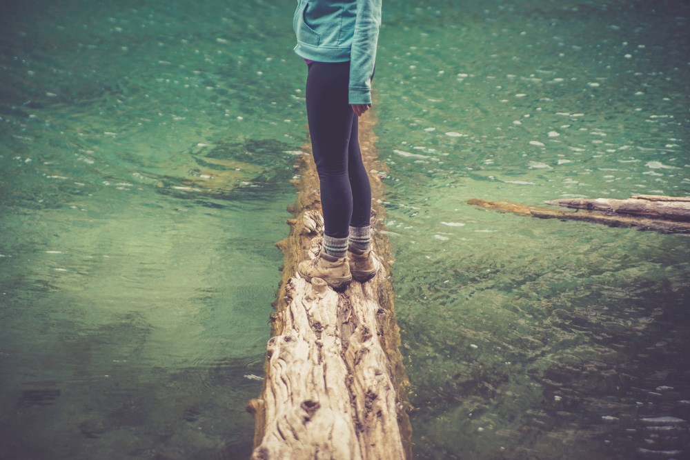 woman standing on log in river woman standing on log in river