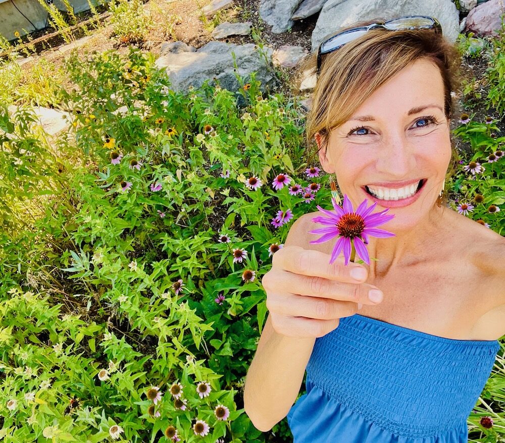 Nicole Apelian holding purple echinacea flower in her garden