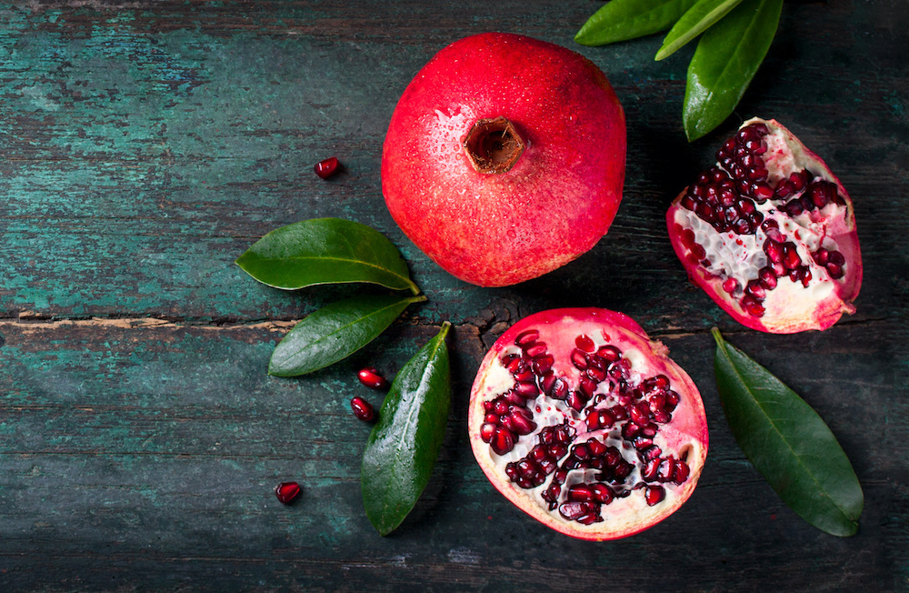 Pomegranate with leaves on wood background Pomegranate with leaves on wood background