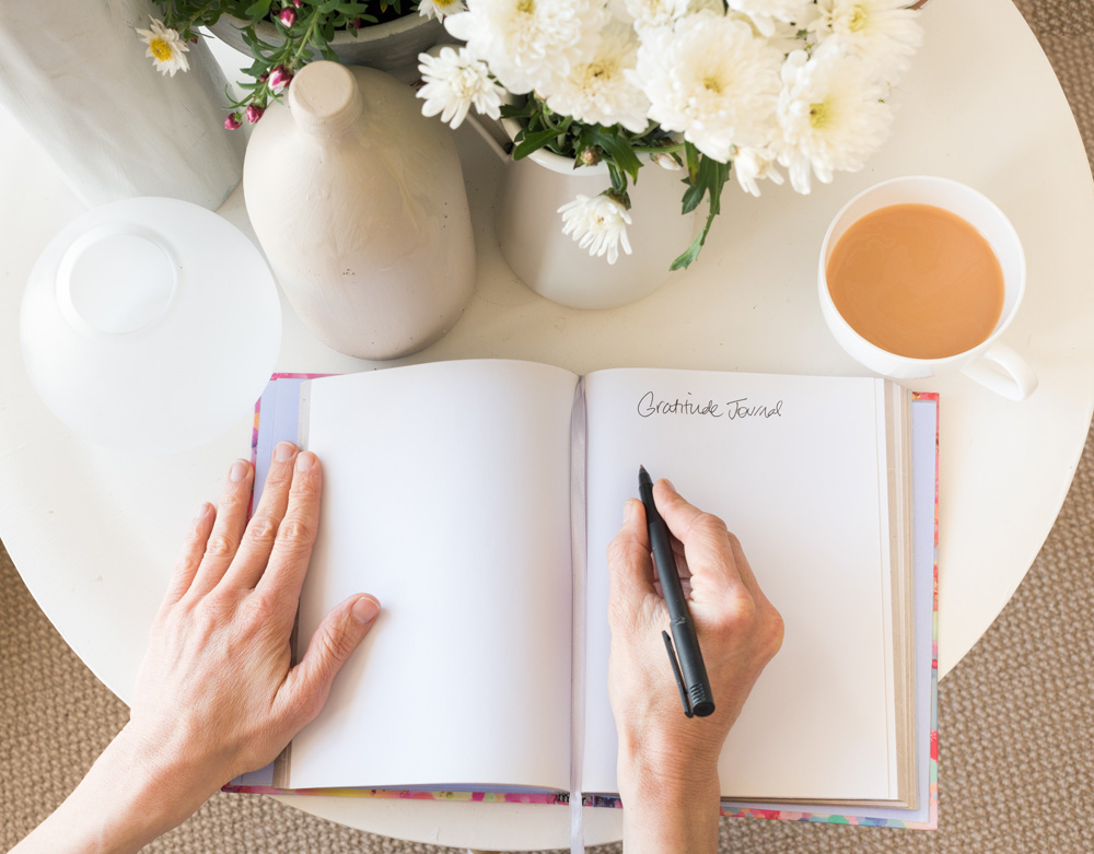 woman's hands writing in gratitude journal woman's hands writing in gratitude journal