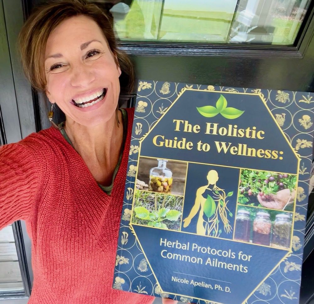 Nicole Apelian holding her Holistic Guide to Wellness book