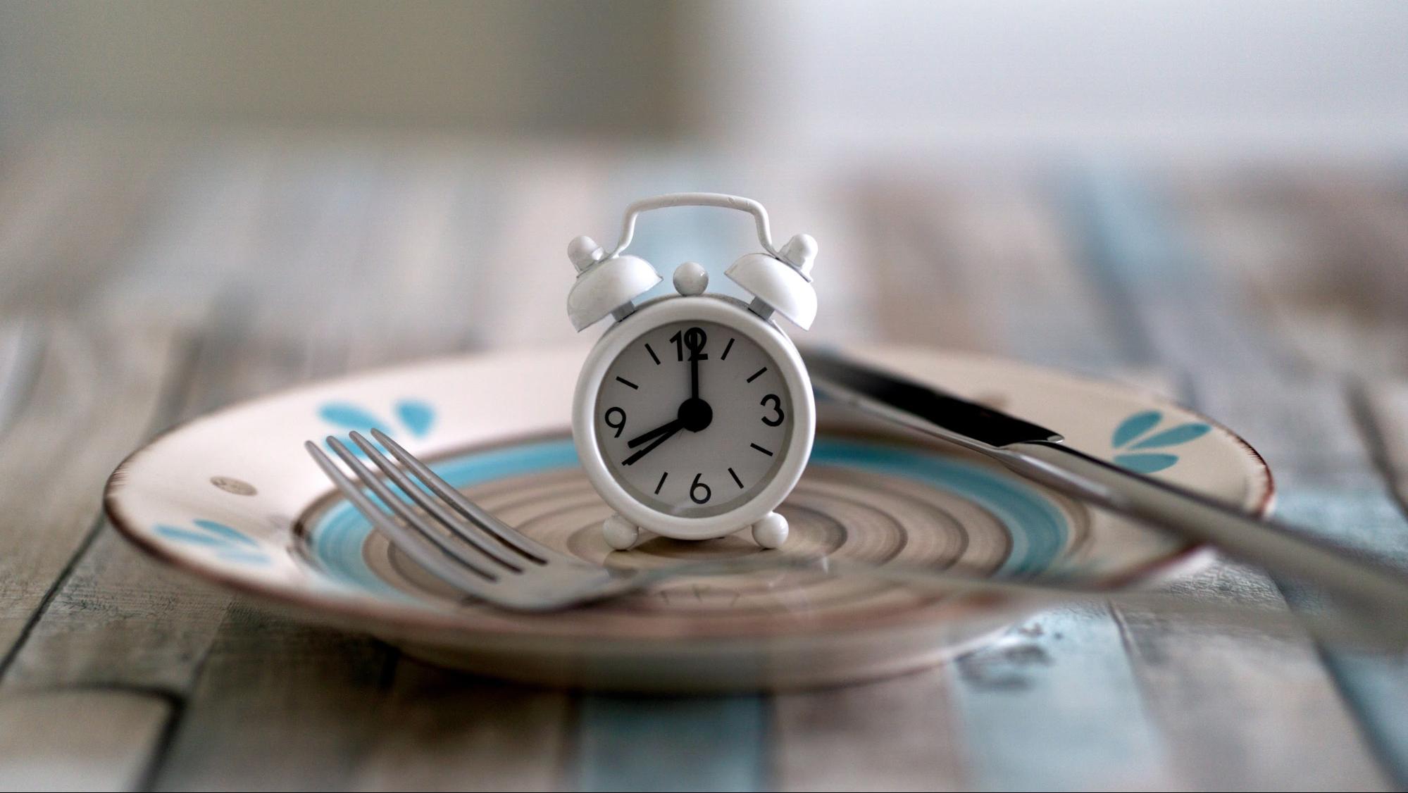 analog alarm clock on plate with silverware analog alarm clock on plate with silverware