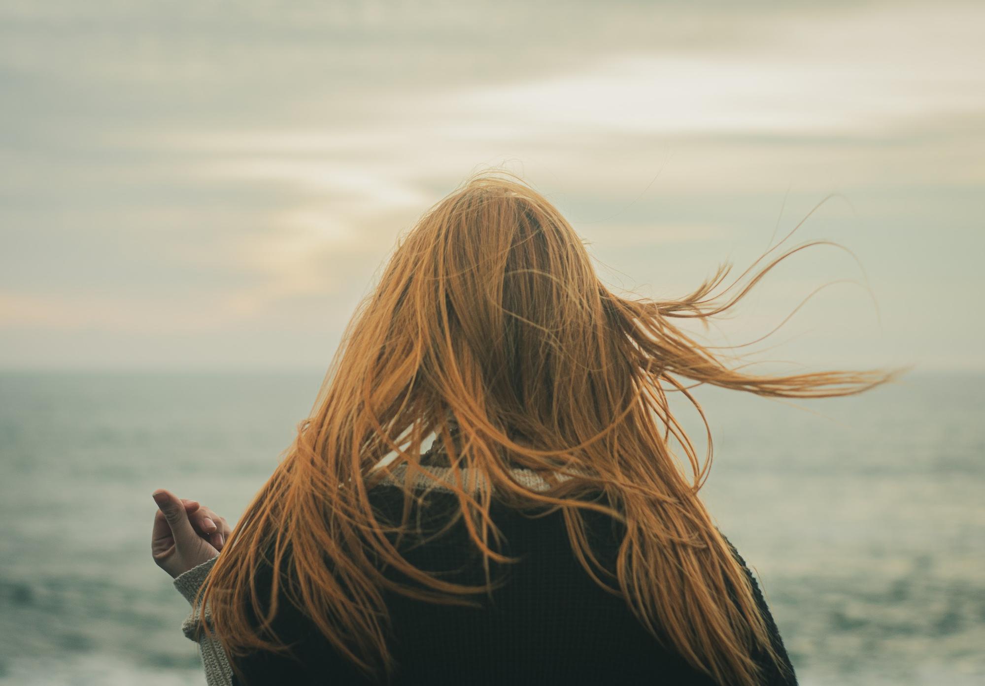 woman with red hair facing the ocean woman with red hair facing the ocean