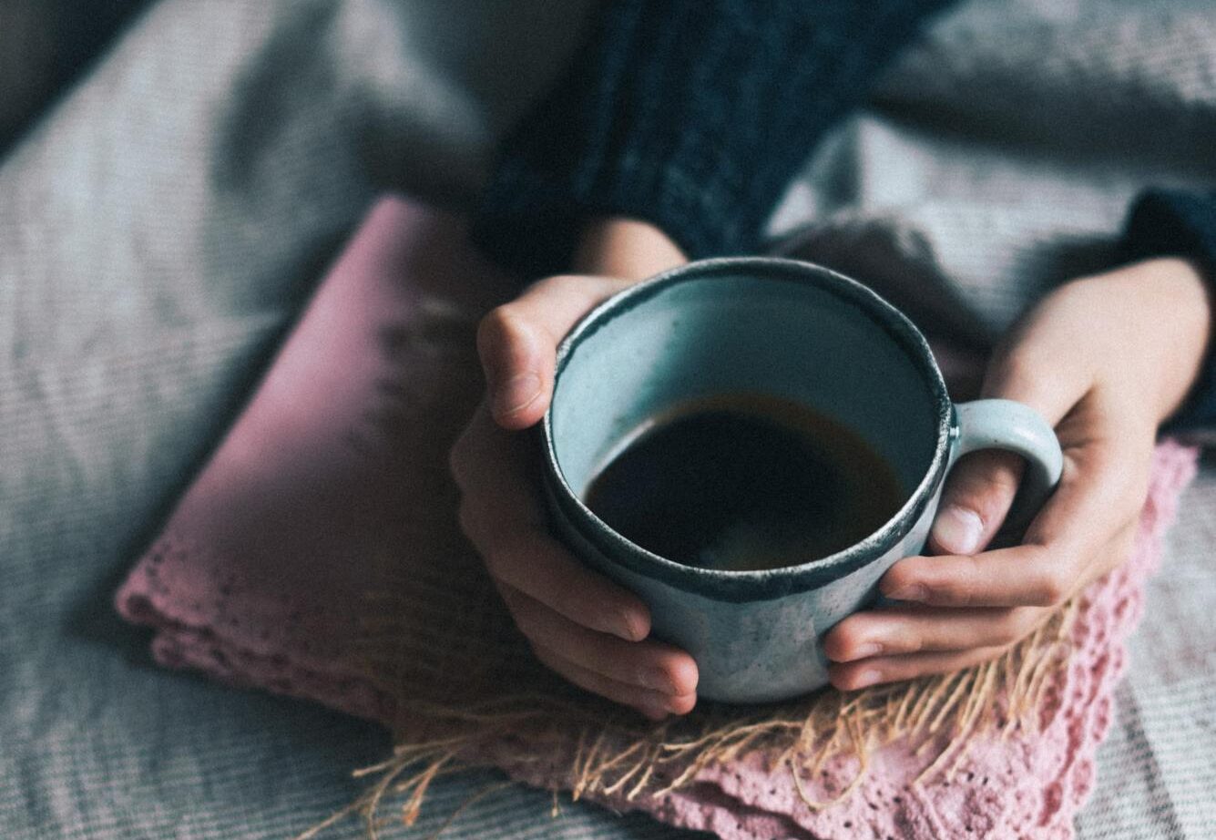 hands holding blue mug of tea