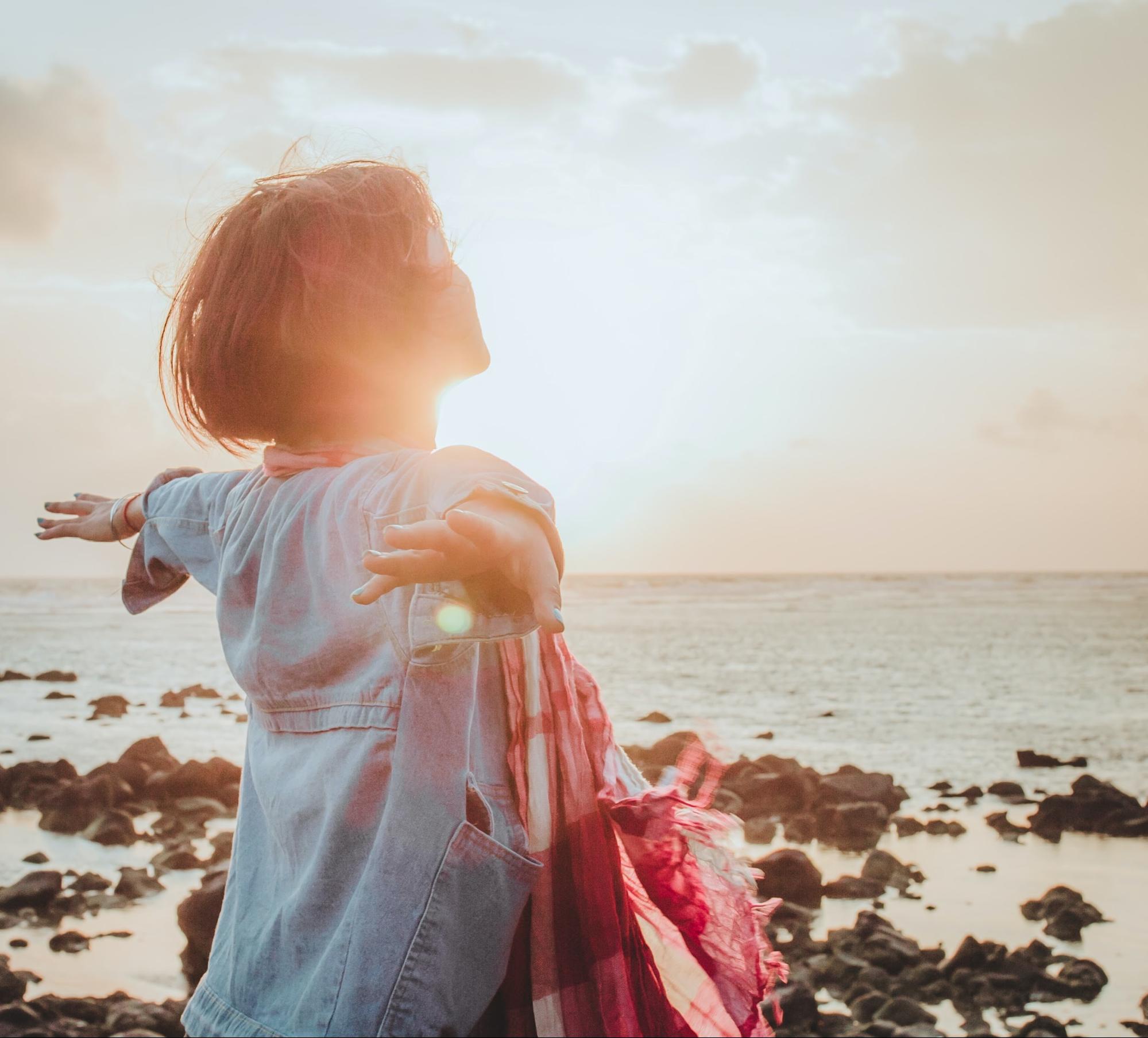 woman with arms open at sunrise