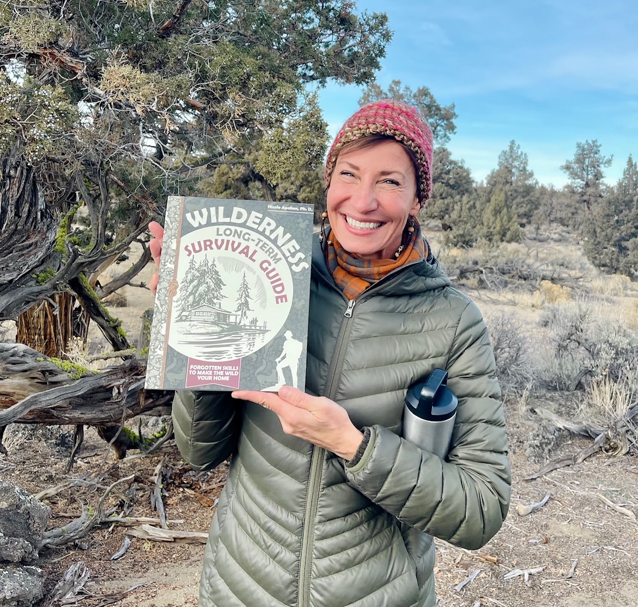 Nicole Apelian holding her Wilderness Long Term Survival Guide book
