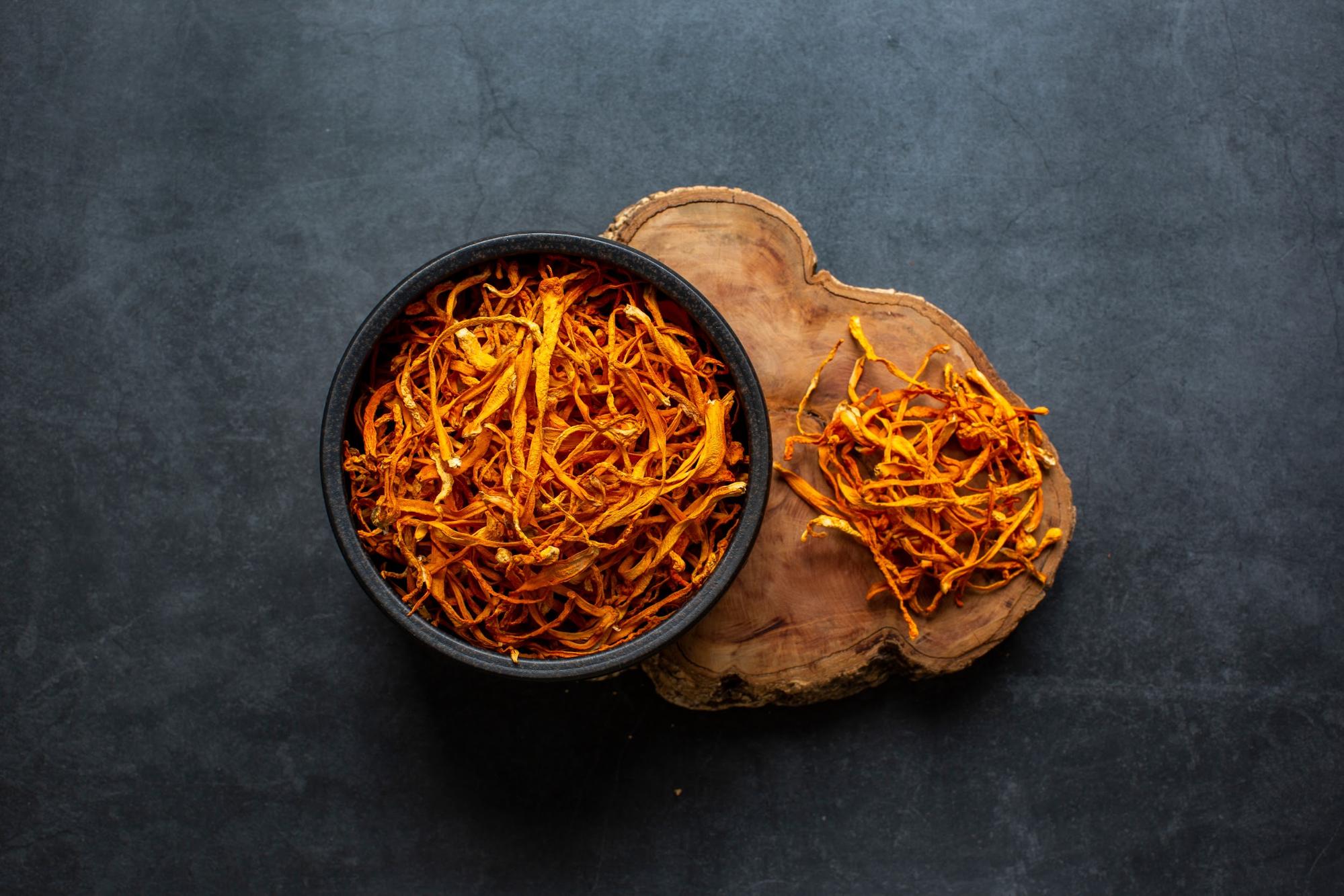 cordyceps mushrooms in bowl on wood slice