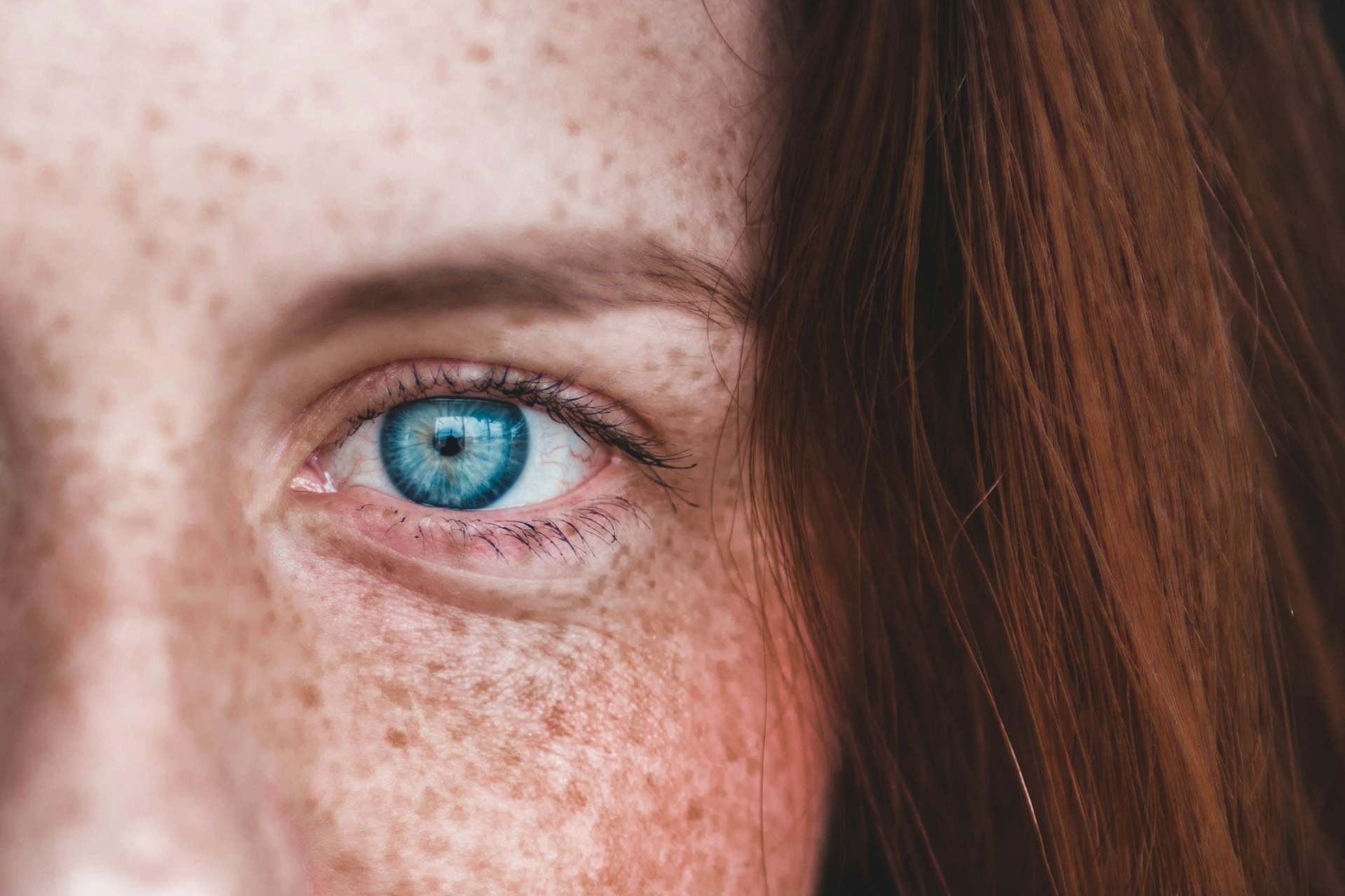 closeup blue eye closeup of blue eye on woman with red hair and freckles