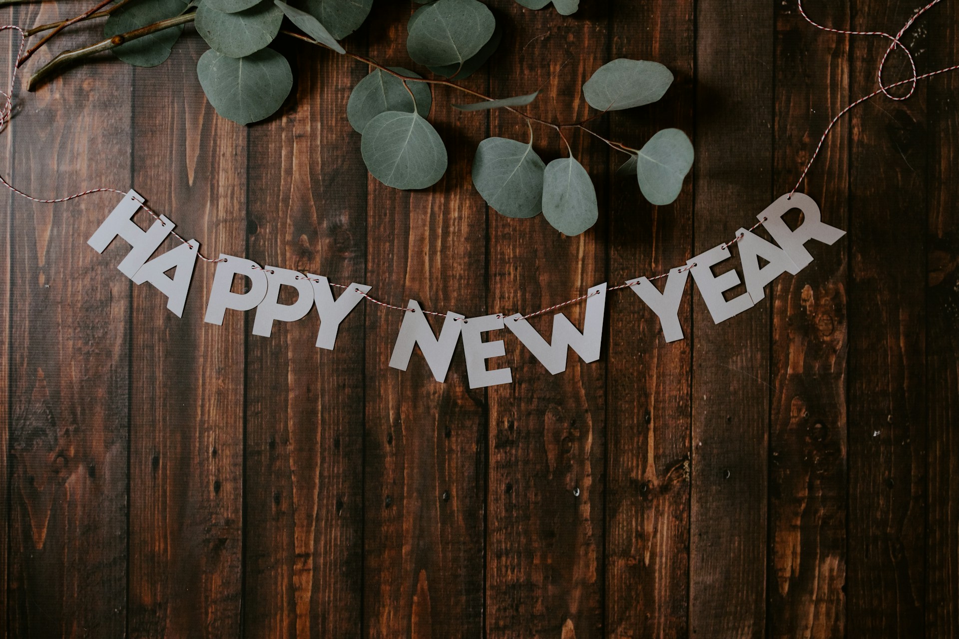 happy new year banner with eucalyptus leaves on wood background